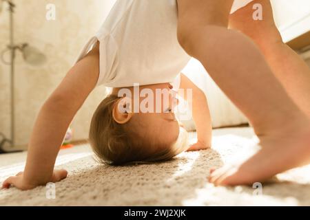 Kleiner Junge im Body, der kopfüber auf einem Schlafzimmerboden steht. Stockfoto