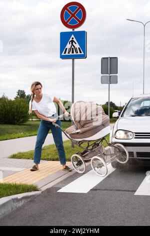 Mutter auf dem Fußweg nach einem Autounfall, als das Fahrzeug ihren Kinderwagen trifft Stockfoto