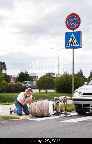 Schockierte Mutter auf dem Gehweg nach einem Autounfall, als ein Fahrzeug ihren Kinderwagen trifft. Stockfoto