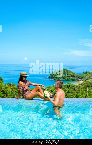 Junge Paar Männer und Frauen am Pool während des Urlaubs auf der tropischen Insellandschaft Mann und Frau im unendlichen Pool Dur Stockfoto