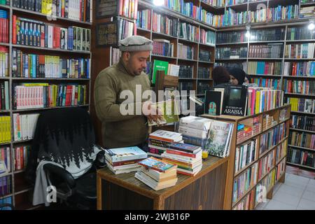 Srinagar, Kaschmir, Indien. Februar 2024. Ein Buchhändler aus Kaschmir passt Bücher in seinem Buchladen „Bestseller“ in Srinagar an. Zum ersten Mal revolutioniert eine Buchhandlung in Kaschmir den Zugang zu Literatur, indem sie Bücher bei 500 Rupien anbietet. Am 12. Februar 2024 in Srinagar Kaschmir, Indien. (Kreditbild: © Firdous Nazir/OKULARIS via ZUMA Press Wire) NUR REDAKTIONELLE VERWENDUNG! Nicht für kommerzielle ZWECKE! Stockfoto