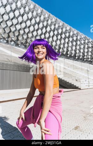 Sorglose aktive Tänzerin in farbenfroher Sportkleidung, die Spaß auf der Straße hat Stockfoto