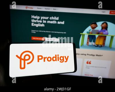 Person mit Smartphone und Logo des US-amerikanischen Online-Lernunternehmens Prodigy Education Inc. Vor der Website. Schwerpunkt auf dem Display des Telefons. Stockfoto