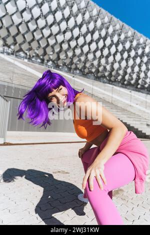 Sorglose aktive Tänzerin in farbenfroher Sportkleidung, die Spaß auf der Straße hat Stockfoto