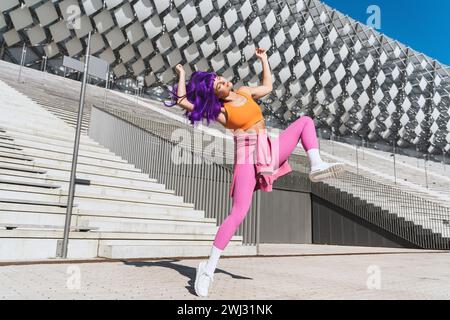 Sorglose aktive Tänzerin in farbenfroher Sportkleidung, die Spaß auf der Straße hat Stockfoto