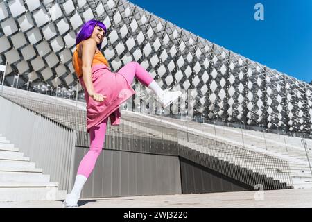 Sorglose aktive Tänzerin in farbenfroher Sportkleidung, die Spaß auf der Straße hat Stockfoto