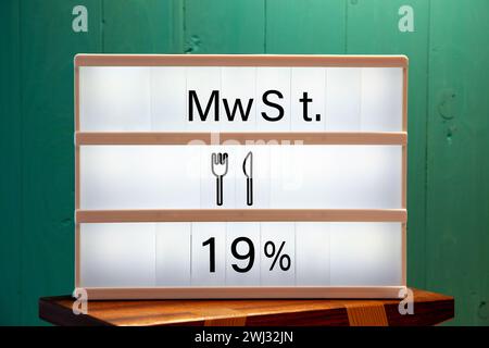 19 % Nachricht auf weißem Schild zu Hause auf einem grünen Regal. Erhöhung der Mehrwertsteuer in der Gastronomie. Stockfoto