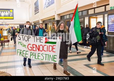Leeds, Großbritannien. FEBRUAR 2024. Pro-palästinensische Demonstranten marschieren durch die Leeds-Station und schwenken Fahnen und Banner. Ein großes Banner lautet: „Stop the Genocide, Free palestine“ Credit Milo Chandler/Alamy Live News Stockfoto