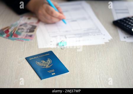 Indonesischer Pass- und Dienstleistungsarbeiter – Tabelle über den Prozess der Registrierung der Staatsbürgerschaft. Weibliche Arbeitnehmerin füllt Papiere über die Staatsbürgerschaft aus Stockfoto