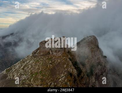 Blick auf das Castello del Volterraio mit Drohne, umgeben von Morgennebel und Wolken Stockfoto