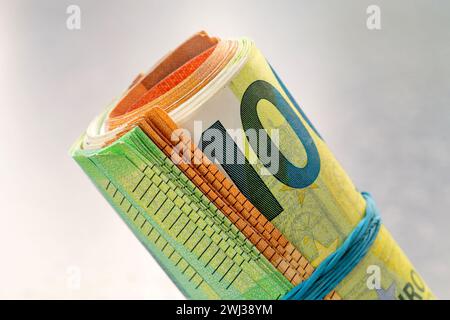 Geldrolle Euro. 100- und 50-Euro-Scheine, die zu einem Schlauch verdreht und mit einem Gummiband gebunden sind. Zusammengefasste EU Stockfoto