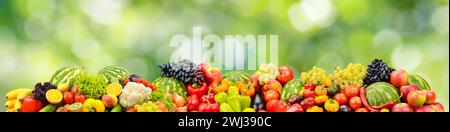 Frisches gesundes Gemüse, Früchte, Beeren auf grünem verschwommenem Hintergrund. Stockfoto
