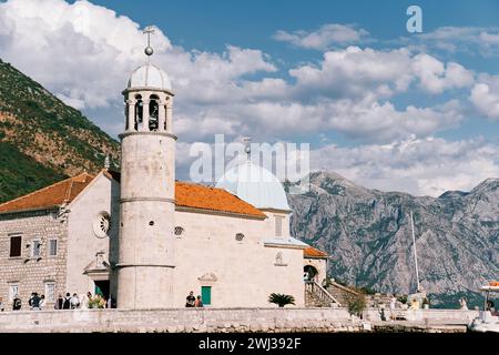 Touristen stehen an der Kirche unserer Lieben Frau von den Felsen auf einer Insel in der Bucht von Kotor. Montenegro Stockfoto