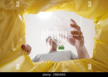 Bild aus dem gelben Recyclingbeutel eines Mannes, der leere Plastikflasche in den Recyclingbehälter wirft Home Recycle ECO Green Zero Concept Stockfoto