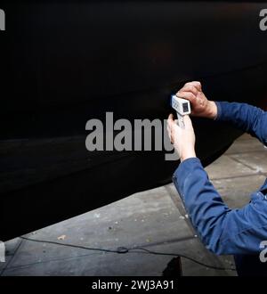 Ein Servicetechniker, der die Dicke des Stahlrumpfes eines Bootes mit einem Ultraschallgerät misst Stockfoto