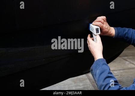 Ein Servicetechniker, der die Dicke des Stahlrumpfes eines Bootes mit einem Ultraschallgerät misst Stockfoto