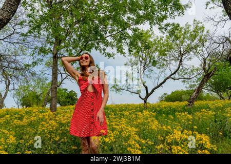 Ein schönes Brünette Model posiert in Einem Feld mit gelben Blumen in Einem Texas Prarie Stockfoto