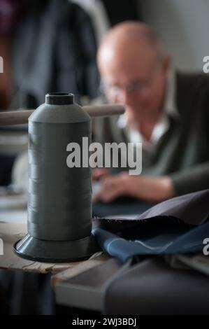 Unerkannter Schneider mit Nähmaschine, Nähkleidung, Mann in der Werkstatt, Stoff in der Hand, Schneiderei Stockfoto