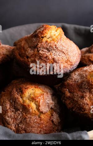 Banana Cinnamon Muffins serviert in einer großen Schüssel: Nahaufnahme eines mit Leinenfutter gefüllten Korbs voller frisch gebackener Frühstückstümmffins Stockfoto