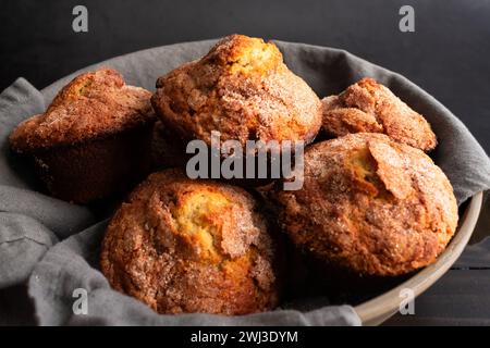 Banana Cinnamon Muffins serviert in einer großen Schüssel: Nahaufnahme eines mit Leinenfutter gefüllten Korbs voller frisch gebackener Frühstückstümmffins Stockfoto