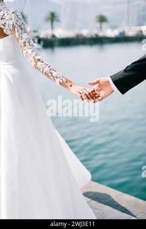 Braut Hand berührt die Palme des Bräutigams, der auf dem Pier steht. Abgeschnitten. Gesichtslos Stockfoto