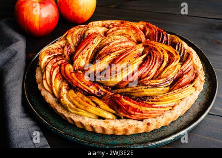 Frisch gebackene vegane Apfeltorte auf einem rustikalen Holztisch: Eine Tarte aus Zimt, geschnittenen Ambrosia, Golden Delicious und Granny Smith Äpfeln Stockfoto