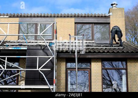 Servicetechniker, die Solarpaneele auf dem Dach eines Wohnhauses installieren Stockfoto