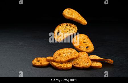 Bruschetta-Cracker, runde Brotcroutons isoliert auf schwarzem Hintergrund Stockfoto
