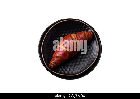 Köstliches knuspriges Croissant mit Schokolade auf einer schwarzen Keramikplatte Stockfoto