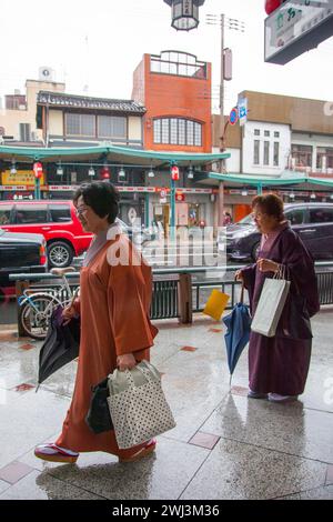 Ältere japanische Frauen tragen Kimonos im Regen auf der Shijo Street in der Innenstadt von Gion, Kyoto, Japan. Stockfoto