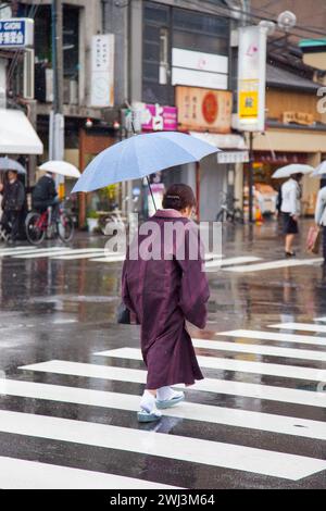 Ältere japanische Frauen tragen Kimonos im Regen auf der Shijo Street in der Innenstadt von Gion, Kyoto, Japan. Stockfoto