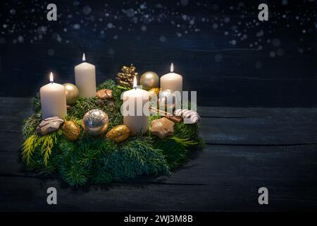 Grüner Adventskranz mit weißen Kerzen, vier für den vierten Adventskranz, Weihnachtsdekoration und Kekse, dunkelblauer Holzrücken Stockfoto