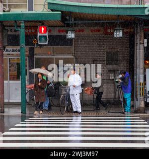 Szene mit Menschen und Verkehr auf der Shijo Street in der Innenstadt von Gion, Kyoto, Japan bei Regen. Stockfoto
