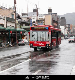 Szene mit Menschen und Verkehr auf der Shijo Street in der Innenstadt von Gion, Kyoto, Japan bei Regen. Stockfoto