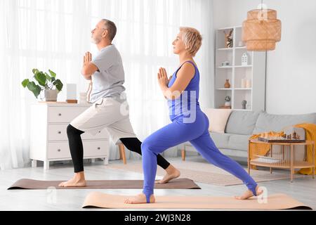 Sportliches reifes Paar, das zu Hause Yoga macht Stockfoto