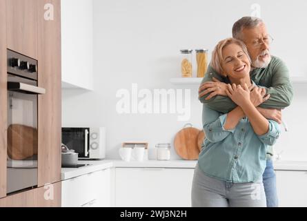 Reifes Paar umarmt sich in der Küche Stockfoto