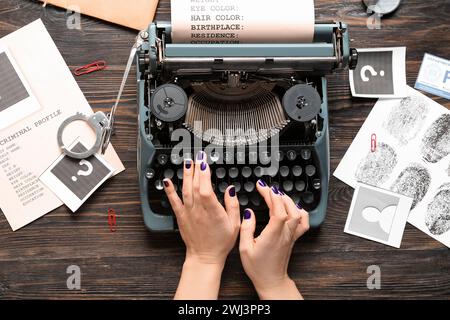 Frau, die auf Schreibmaschine und kriminellen Akten auf hölzernem Hintergrund schreibt Stockfoto