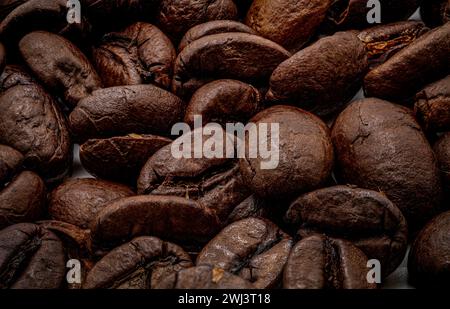 Eine Nahaufnahme brauner ganzer Kaffeebohnen mit Textur und dunkler Farbe, die Haine der Bohnen in einem zufälligen Muster sehen. Stockfoto