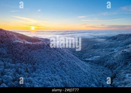 Blick aus der Vogelperspektive auf die Hügel in der Nähe des Heiligtums von Oropa im Winter bei Sonnenaufgang. Biella, Bezirk Biella, Piemont, Italien, Europa. Stockfoto