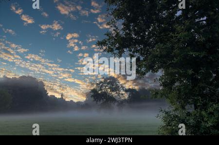 Dawn's Whisper: Nebel und Sonnenaufgang auf dem Land Stockfoto