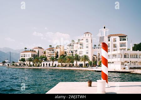 Rot gestreifter Leuchtturm mit Solarpaneel steht auf einem Pier vor der Küste von Porto. Montenegro Stockfoto