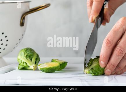 Eine Nahaufnahme der Hände, die frische Rosenkohl zum Kochen vorbereiten. Stockfoto