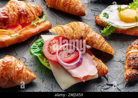 Croissant-Sandwichsortiment. Verschiedene gefüllte Croissants auf Schwarz Stockfoto