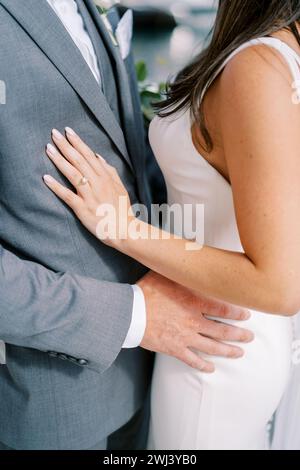 Der Bräutigam umarmt die Braut an der Hüfte, während er auf der Straße steht. Abgeschnitten. Gesichtslos Stockfoto