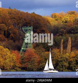 Ein Segelboot im Herbst mit der Förderstruktur der Zeche Carl Funke, Baldeneysee, Essen Stockfoto