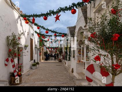 Straße im Rione Monti-Viertel von Alberobello mit Trulli-Häusern und -Hütten und farbenfroher Weihnachtsdekoration Stockfoto