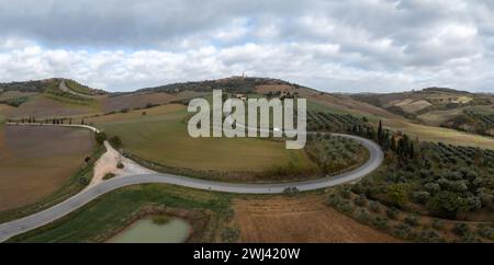 Eine lange kurvige Straße führt zum toskanischen Dorf Pienza auf einem Hügel Stockfoto