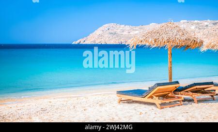 Mykonos Strand im Sommer mit Sonnenschirm und luxuriösen Liegestühlen, blauer Ozean Griechenland Stockfoto