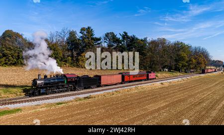 Aus der Vogelperspektive eines antiken restaurierten Dampfpassagiers - Güterzug, der an einem Herbsttag durch landwirtschaftliche Felder fährt Stockfoto