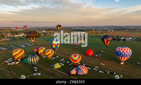 Aus der Vogelperspektive sehen Sie mehrere Heißluftballons, die während eines morgendlichen Starts an einem sonnigen Sommertag aufsteigen Stockfoto